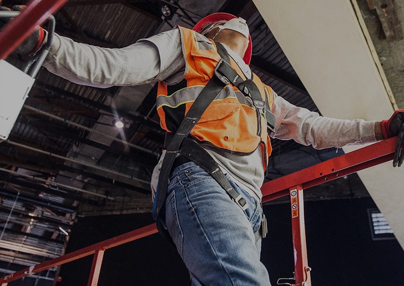 Man inspecting ceiling in orange vest and mask
